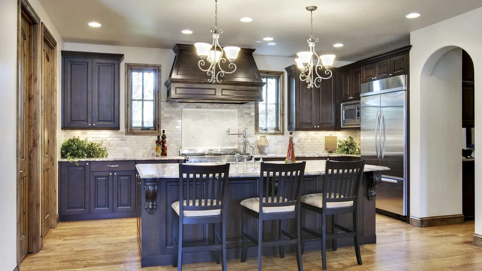 Finished kitchen interior with white cabinetry, a central island and pendant lighting.