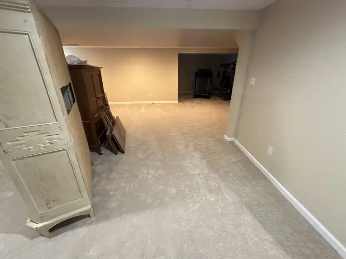 Basement living area after cleanup, with belongings removed and the light floor surface exposed.