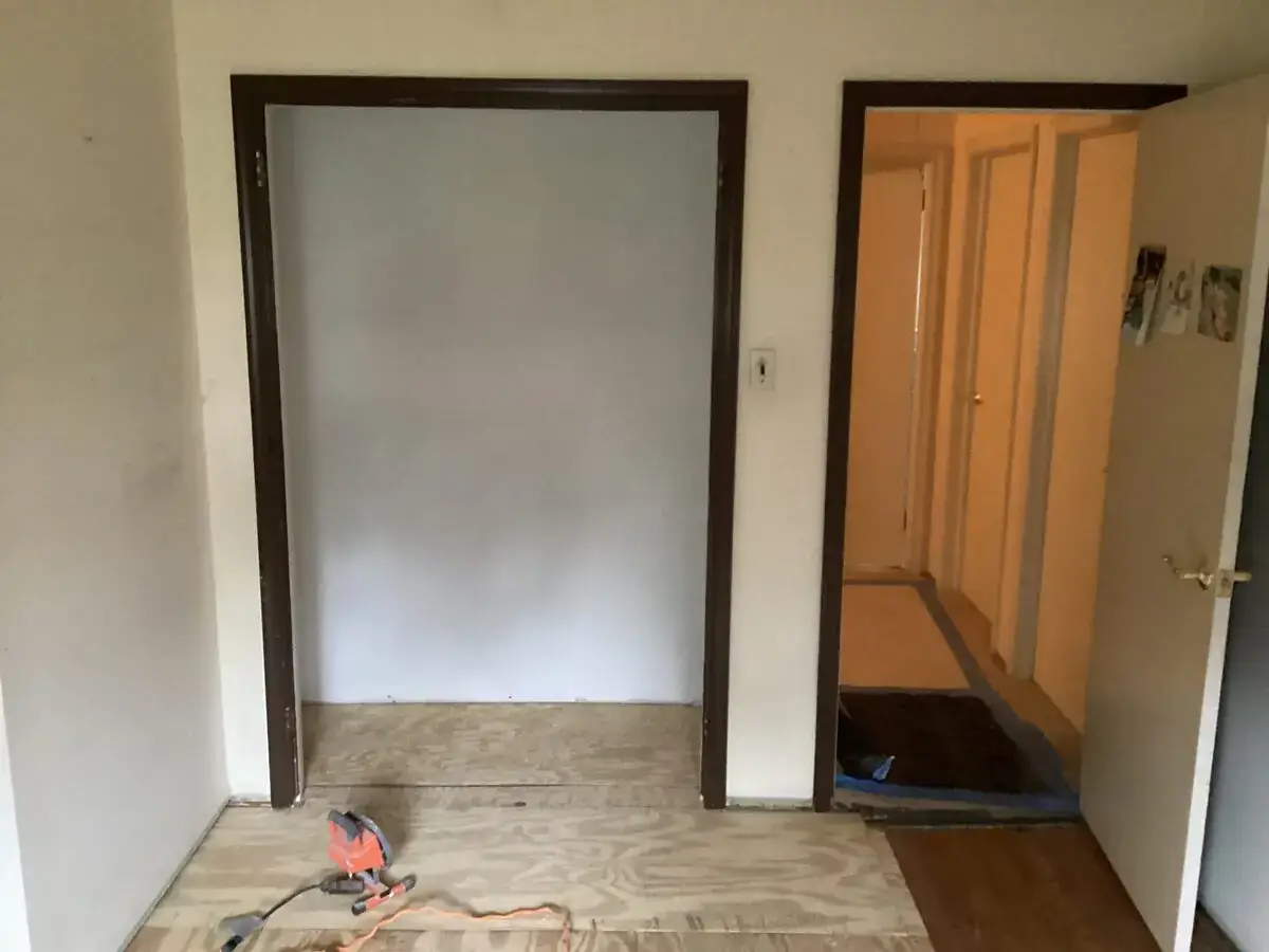 Closet area after affected lower materials were removed, with the subfloor exposed for repair.